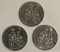 Reverse side of the three 1979 Canadian 50 cent coins with Canadian Coat of Arms and denomination markings.
