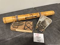 Three antique musical instruments placed on a table including two thumb pianos and one bamboo tube percussion instrument, front view