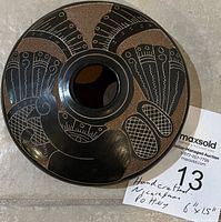 Top view of carved and painted pottery bowl showing detailed decorative design in black on brown clay.