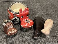 Four carved soapstone hippo figurines with a decorated soapstone bowl, showing colors, designs, and relative sizes.