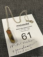 Photo showing the full 18 inch sterling silver chain with the gemstone pendulum pendant laid out on a surface with auction information.