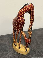 Front angled view of the wood carved giraffe mother and calf statue showing detailed paint and craftsmanship.