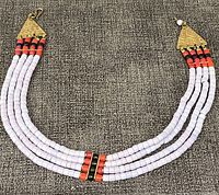 Full view of the four-strand handcrafted beaded necklace laid flat, showing white, red, and black beads with metal triangular connectors at each end.