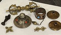 All items arranged on white background showing entire lot including vajra, incense burner, bracelet, candle holders, and ceremonial brass items.
