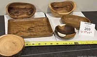 Top view of six wooden items including bowls and a rectangular tray showing natural wood grain and polished finishes.