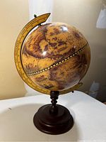 Full view of antique-style globe showing sepia and earth tone map design with spinning wooden base.