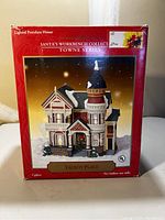 Box of porcelain house with product image and labeling indicating model Talbot Place from Santa's Workbench Collection Towne Series.