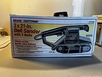 Box of Sears Craftsman 3 x 21 inch belt sander with 2 belts, original packaging showing product illustration and branding.