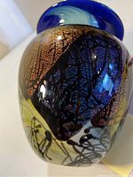 Close-up view of the dichroic glass vase showing the detailed abstract pattern, iridescent colors of blue, purple, black, and sparkly orange-gold crackled sections.