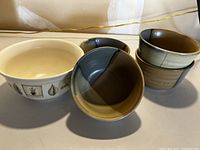 Five bowls displayed, four matching with green and brown tones, one small with herb pattern