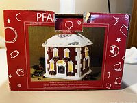 Photo of the original box showing Pfaltzgraff Sculpted Holiday House Decoration with a picture of the house on the front and holiday graphics on the box.