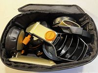 Carrying case containing multiple Ryobi AirGrip attachments, all silver and black with orange buttons, showing good physical condition but dusty.