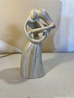 Front view of abstract stone sculpture depicting two intertwined people embracing.