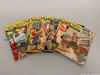 Front view of 7 vintage Classics Illustrated comic books mainly showing the covers of Moby Dick, Rip Van Winkle and the Headless Horseman, Don Quixote, and others in a fanned display.