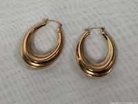 Top view of the 10K gold oval hoop earrings displaying the overall shape and color.