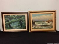 Two framed and signed oil paintings displayed side by side on a black background, showing full views of each frame and painting.