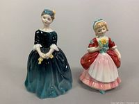 Front view of two Royal Doulton porcelain figurines standing side by side on a white background, showing colors and details clearly.