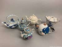Photo showing all six porcelain teapots together in one shot with good lighting to illustrate variety and condition