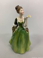 Front view of the Royal Doulton porcelain figurine showing the woman standing with a green dress and yellow flower in hand.