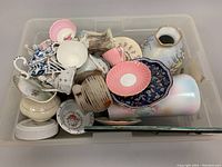 Full top view of the bin filled with assorted miscellaneous chinaware and ceramic pieces in various floral patterns and pastel colors.