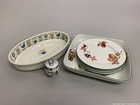 Johnson Bros oval dish with border decoration, Royal Worcester square dish with fruit motifs, four plates stacked, and egg coddler in front