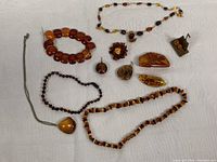 Overview of assorted vintage natural amber jewelry pieces showing beaded necklaces, brooches, pendant and earrings