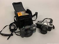 Overall lot shot: Pentax K1000 SLR, Zoom 105 Super compact, carrying case with manuals and film boxes visible