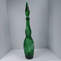 Full view of the tall green handblown Empoli glass decanter with stopper showing textured vertical stripes on the body and elongated stopper.