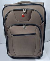 Front view of the brown SwissGear suitcase showing front zippered compartments and logo.