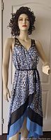 Full view of sleeveless V-neck summer dress on mannequin, showing abstract print, black lattice straps and layered skirt