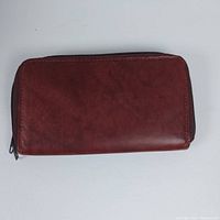 Front view of the brown vintage leather wallet showing the main zipper closure and smooth leather surface.
