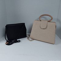 Two vintage evening bags, one beige with rounded handle, one black with corded strap together on white background.
