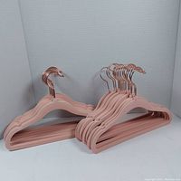 Set of 20 pink velvet children's hangers with rose gold hooks neatly stacked.