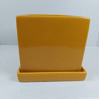 Front view of square mustard yellow glazed planter with matching saucer shows smooth glossy finish and clean edges.