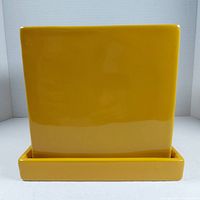 Front view of yellow glazed ceramic planter with attached matching saucer, showing smooth glossy finish and square shape.