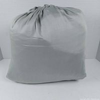 Packaged sheet set in sage green fabric, drawn closed with elastic and drawstring at top.