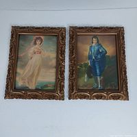 Two vintage framed art prints titled 'Pinkie' and 'Boy Blue' hanging side by side, showing ornate wood frames and detailed prints