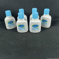Six 60 ml bottles of Cetaphil Gentle Skin Cleanser with blue caps, arranged in two rows on a black fabric surface.