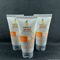 Photo showing three tubes of Garnier Ombrelle Sport Endurance Sunscreen SPF 30 standing upright on a dark background.