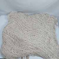 Folded off-white woven rope hammock showing diamond mesh knit material layout.