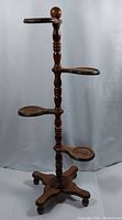 Full view of the vintage wooden plant stand showing four shelves on a turned central column and tripod base.