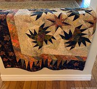 Front view of quilt draped showing maple leaf pattern and inner and outer borders.