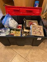 Plastic tote open showing multiple boxes of Christmas led and glass ornaments and bags of decorative picks.