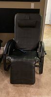 Full front view of the black massage chair showing padded headrest, armrests, and footrest extended.