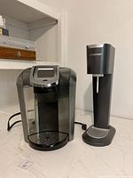Front view of Keurig coffee maker and SodaStream carbonator machine side by side.