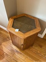 Front and top view showing hexagonal shape, oak wood construction with glass inset top and vertical slatted sides with doors.