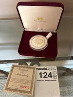 Coin displayed in burgundy velvet fitted case with cream interior bearing Maple Leaf Mint logo. Certificate of authenticity with red serial number 000450 included beside the coin.