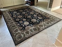 Full view of the Persian area rug laid out on tiled floor near front doors.