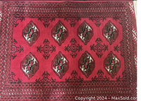 Full view of Persian area rug lying flat on carpeted floor showing red tones and geometric medallion pattern.