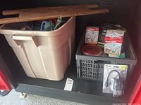 Photo of the storage bin with two boxes of 100W Reactor flood light bulbs, a small plastic basket with timer and small cord accessories, and wooden sticks resting on top.